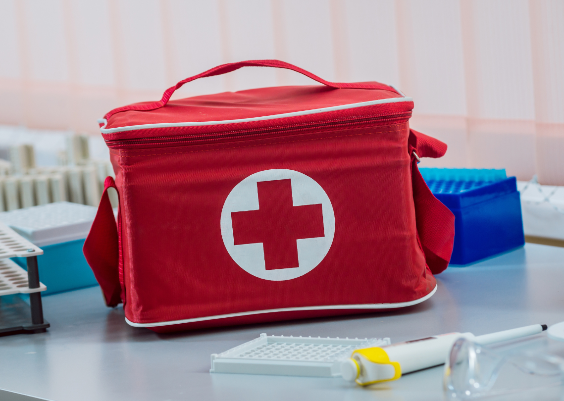 Red first aid bag on a laboratory table with medical equipment nearby.