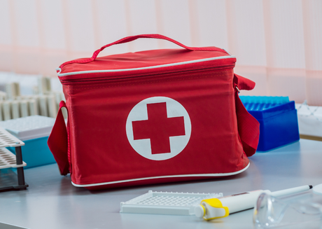 Red first aid bag on a laboratory table with medical equipment nearby.