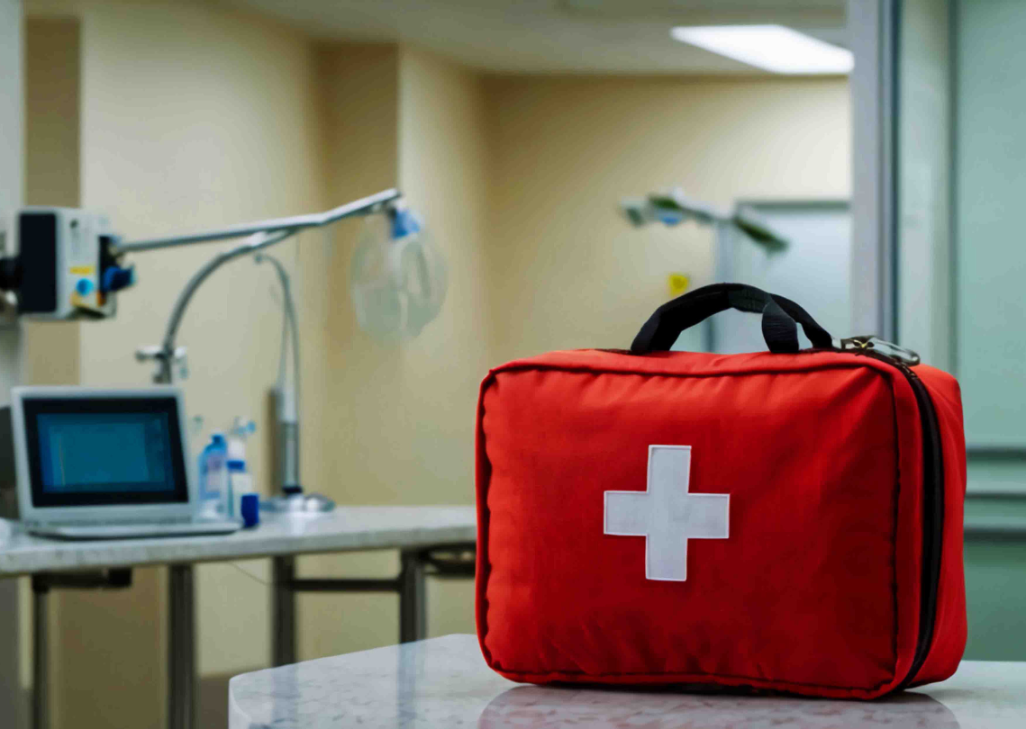Red first aid kit with a white cross on a table in a medical room