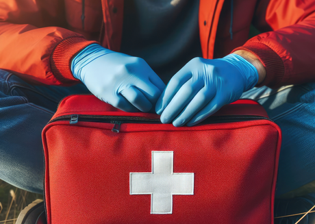 Person in blue gloves opening red first aid kit outdoors