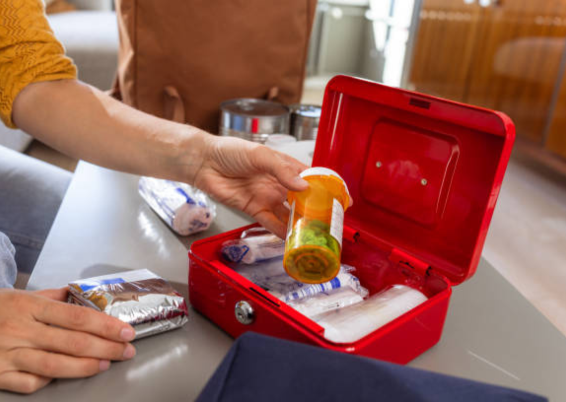 Red first aid kit with medical pills and gauze.