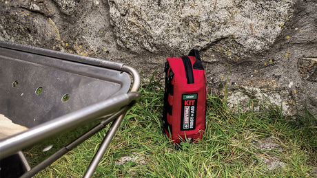 Red first aid kit on grass by a stone wall