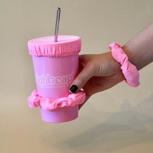 NightCap scrunchie worn on the wrist and pulled over a cup as a drink cover with a straw