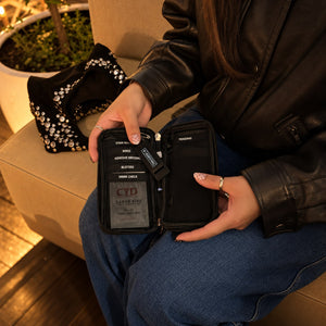 Woman in a leather jacket opening the SURVIVAL Safe Night Out KIT, showing the drink spike test and labelled loops